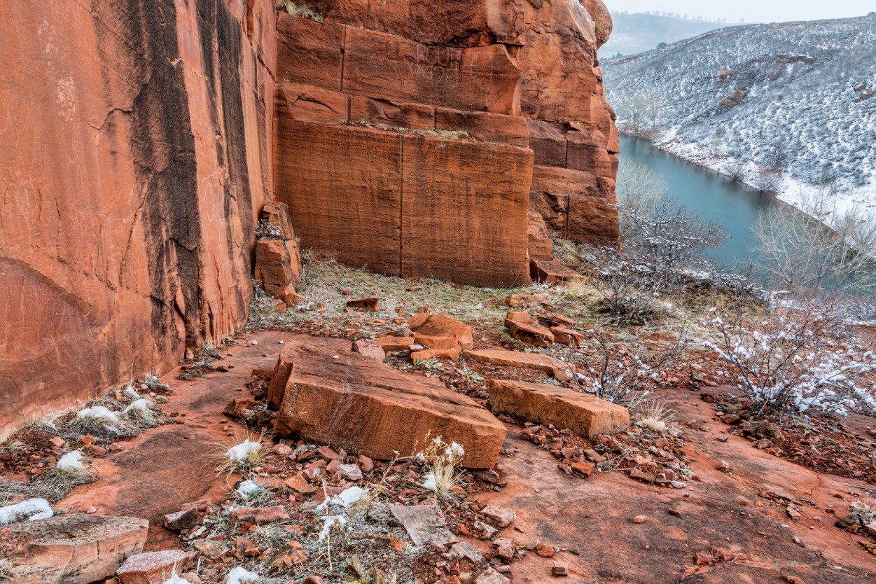 history of quarrying in colorado represented by a red stone canyon in the colorado mountains with snow around and a river in the distance